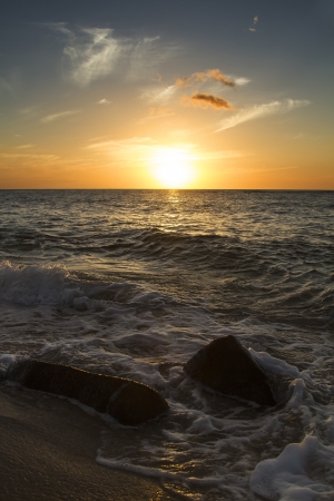 small waves rolling over rocks at the beach during sunsetの写真素材