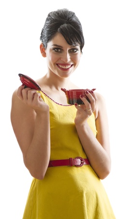 young woman with 60's inspired style, smelling a small red crockpotの写真素材
