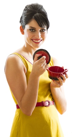 young woman with 60's inspired style, smelling a small red crockpotの写真素材