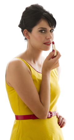 Young woman wearing a bring yellow dress looking at the camera while applying lipstickの写真素材