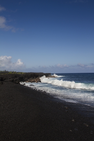 Black stone beach shore on the Big island of Hawaiii being pounded by waveの写真素材