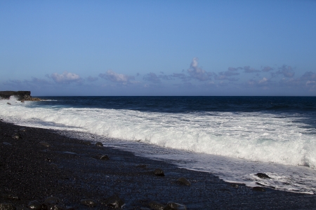 Wave crashing on a black sand beach in Hawaiiの写真素材