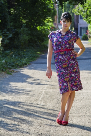 Young fashionable woman wearing a multi colored flower pattern dress standing in an urban alleyの写真素材
