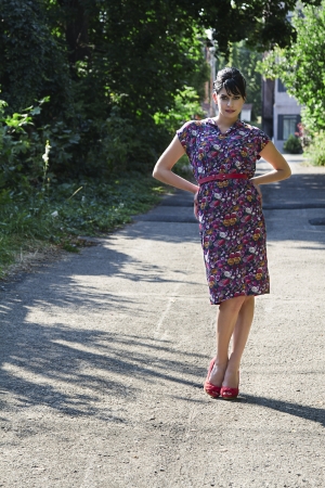 Young fashionable woman wearing a multi colored flower pattern dress standing in an urban alleyの写真素材