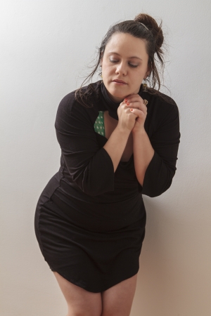 Woman wearing a black dress with wispy flowing hair holding her hand in praying position with her eyes closedの写真素材