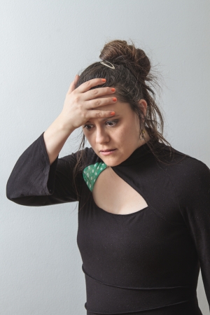thirtie something brunette woman with hand on her forehead and puzzled lookの写真素材