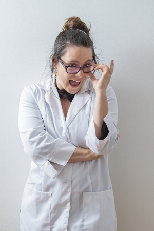 thirtie something brunette woman wearing a lab coat holding her glasses with a big funny smileの写真素材