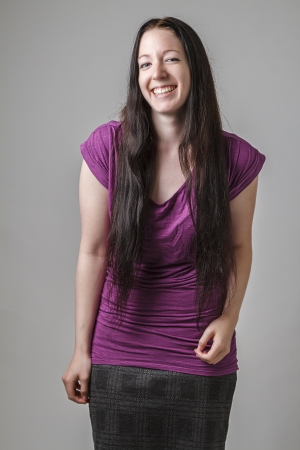 young woman with long black hair and a purple shirt, in the middle of cracking up laughingの写真素材