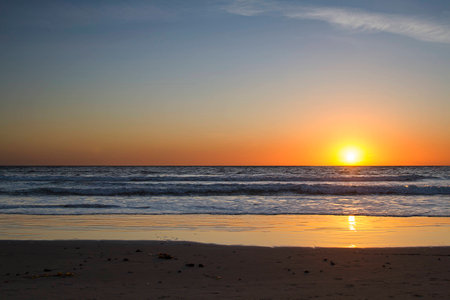 bright sunset at a beach over the calm pacific oceanの写真素材