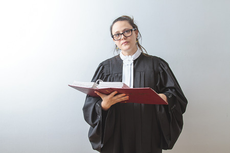 thirty something brunette woman wearing a canadian lawyer toga reading a red criminal law bookの写真素材