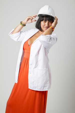Young philipino engineer, wearing a sexy orange dress, hard hat and a lab coatの写真素材