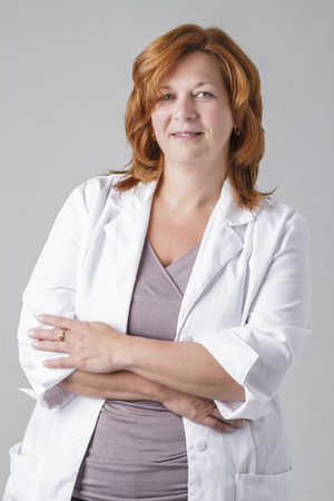 forty something woman doctocr with red hair, against a gray backgroundの写真素材