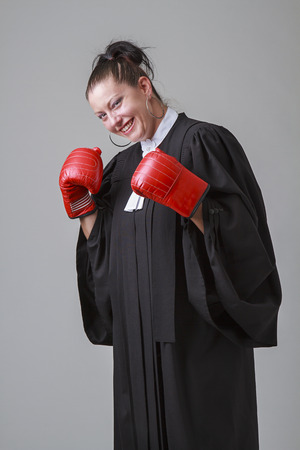 Woman in her thirties wearing a canadian lawyer toga, knocking back her fist to punchの写真素材