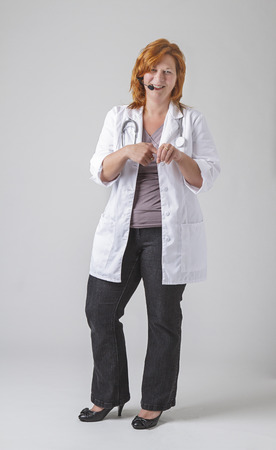 red hair female doctor, with headset and stethoscope, showing inserting with fingerの写真素材