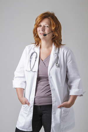 forty something woman doctor with red hair with a stethoscope and a headsetの写真素材