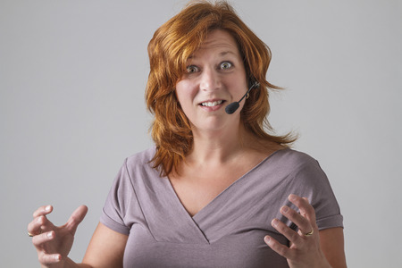 red hair female phone agent with headset with angry expressionの写真素材