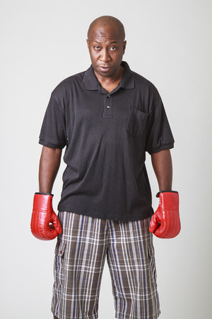 bald black men in his forty, wearing polo and short, with red boxing glovesの写真素材