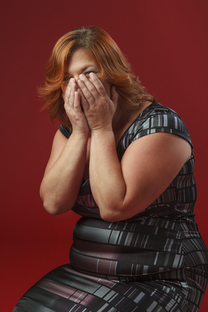 woman on her knees hidding her laugh inside her handsの写真素材