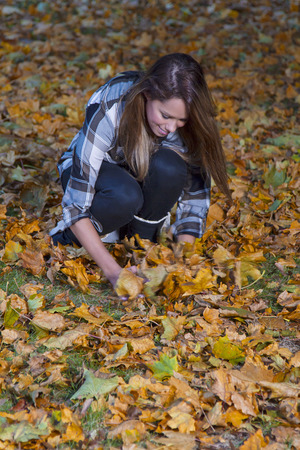 young woman picking up dead leavesの写真素材