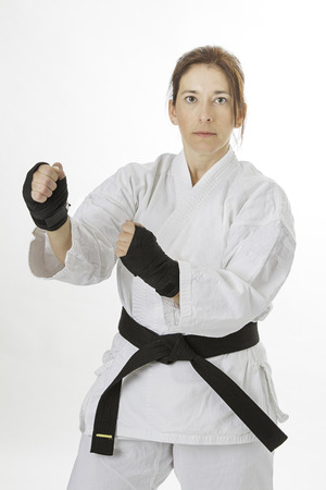 woman in her fortie, wearing black hand protector and a martial art uniform in fighting positionの写真素材