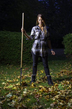 twenty something girl holding a rake at nightの写真素材