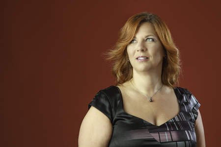 forty year old woman, looking up, with red hair against a red backgroundの写真素材