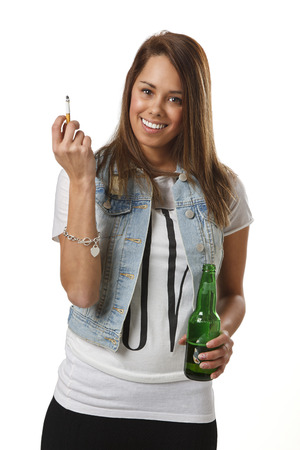 twenty something girl in trendy outfit, with a cigarette and a green bottle of beerの写真素材