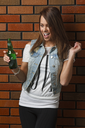 happy young woman with a green bottle of beerの写真素材