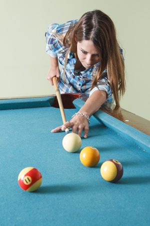 young woman wearing a low cut plaid shirt, playing poolの写真素材