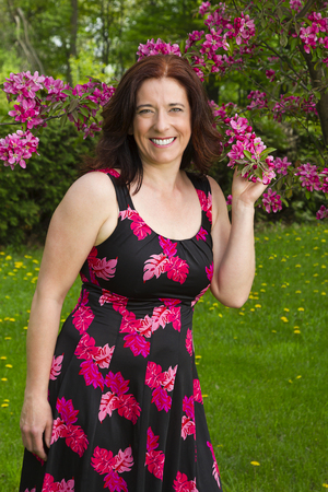 forty something woman wearing a summer dress, smelling cherry blossomsの写真素材