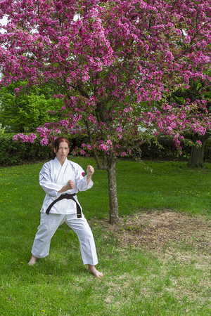 woman in martial art stance under a cherry tree in bloomの写真素材