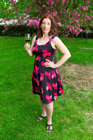 forty something brunette woman wearing a sun dress enjoying a glass of wineの写真素材