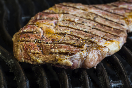 large steak, with ground pepper, on a bbq grilの写真素材