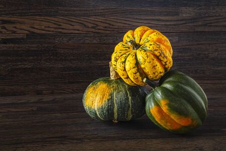 two Sweet Dumpling squash and one Kabocha squash in a stack against a wood backgroundの写真素材