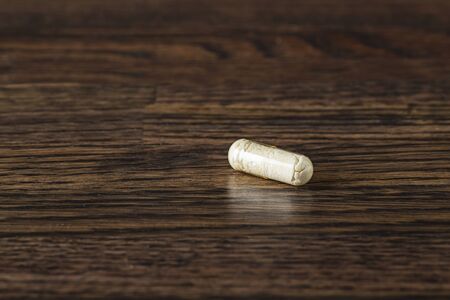 close-up of a transparent pill packed with white ingredient against a dark wood backgroundの写真素材