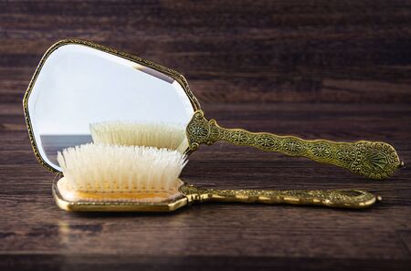 antique hand mirror and hair brush against a dark wood backgroundの写真素材