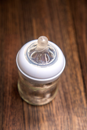Top view of a small baby bottle against a dark wood background