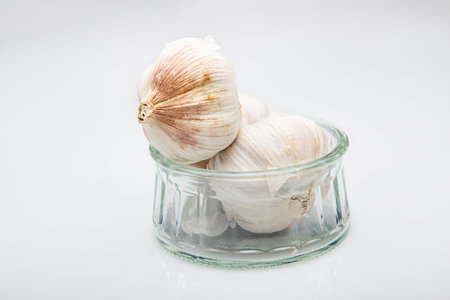 Bulb of galic, in a glass bowl, against a white backgroundの写真素材