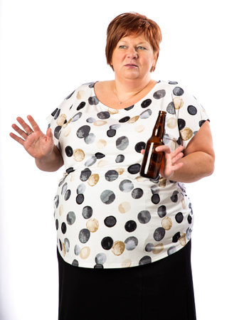 Isolated portrait of a red hai, fifty year old woman, holding  a bottle of beer with a questionning expressionの写真素材