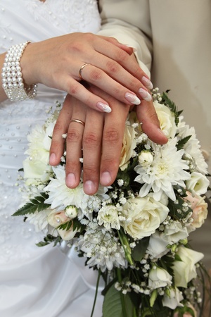 Hands of a newly-married couple on a bunch of flowersの写真素材