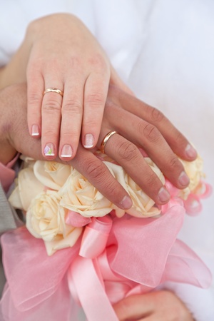 Hands of the groom and the bride with wedding rings on a wedding bouquetの写真素材