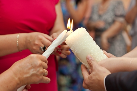 The burning candle in the hands of the newly married coupleの写真素材