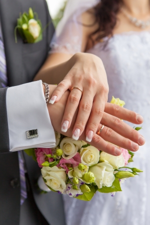 Hands with wedding rings and a wedding bouquetの写真素材