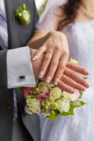 Hands with wedding rings and a wedding bouquetの写真素材