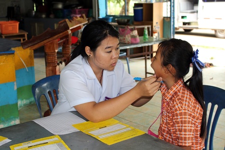 UDONTHANI, THAILAND â JUNE 12, 2018:  Doctor,  she is checking the oral cavity of a student,  be health tooth preservation to her,  in BAN HUA KUA MUEAD AE school at UDONTHANI province THAILAND.のeditorial素材