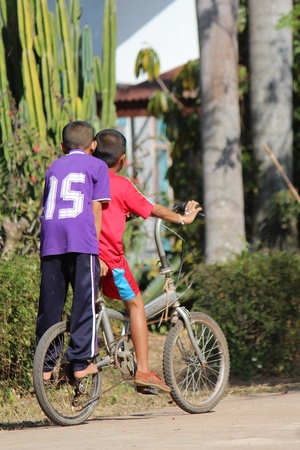 UDONTHANI, THAILAND â FEBRUARY 1, 2019 :  Two Asian boys, they are riding bicycle in front of school building,  they will be getting back to their home after play together at the playground.のeditorial素材