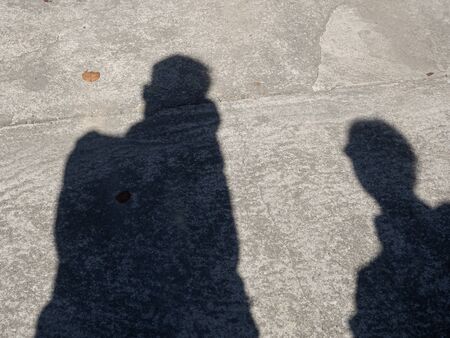Shadows of men and women on the concrete road with patterns and lines