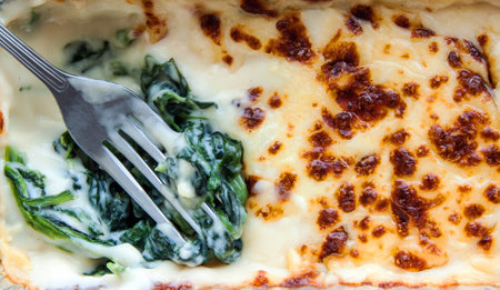 close up fork baked spinach with cheese in froid package on isolateの写真素材