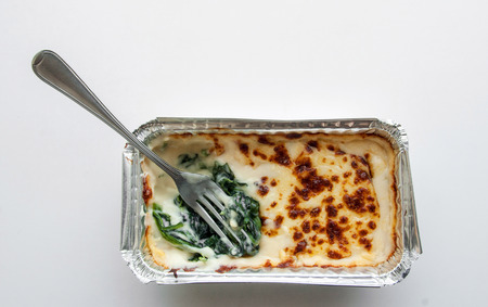 close up fork baked spinach with cheese in froid package on isolateの写真素材