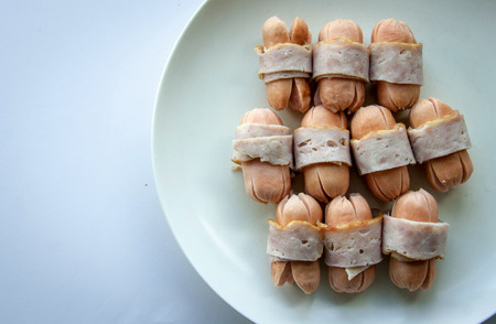 close up boiled bacon wrapped sausageson whiteの写真素材